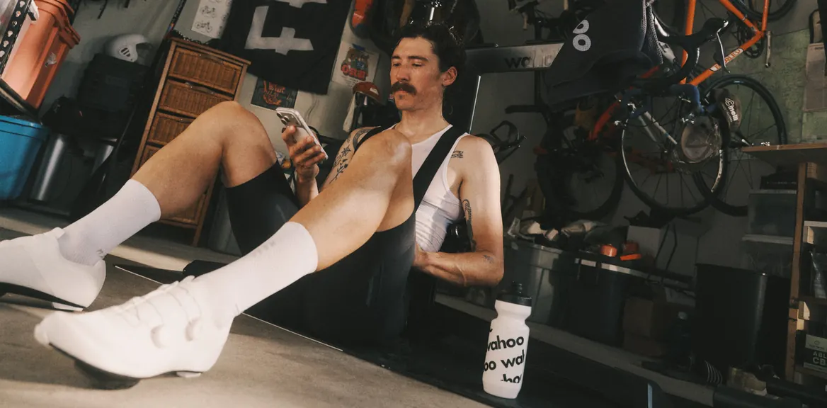 A rider resting against a workshop bench with a Wahoo bottle